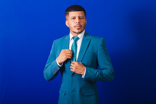 Uomo di colore brasiliano vestito con giacca e cravatta blu uomo d'affari che fissa cravatta