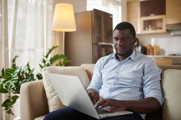 Uomo di colore che controlla le email sul computer portatile