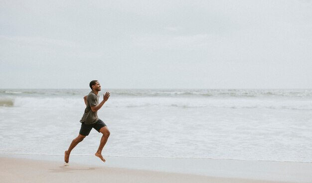 Uomo di colore che corre sulla spiaggia