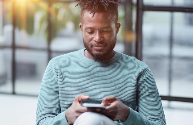 Uomo di colore che guarda lo smartphone navigando in Internet per la tecnologia dell'ufficio e la comunicazione digitale