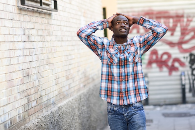 Uomo di colore che indossa vestiti casuali nella priorità bassa urbana