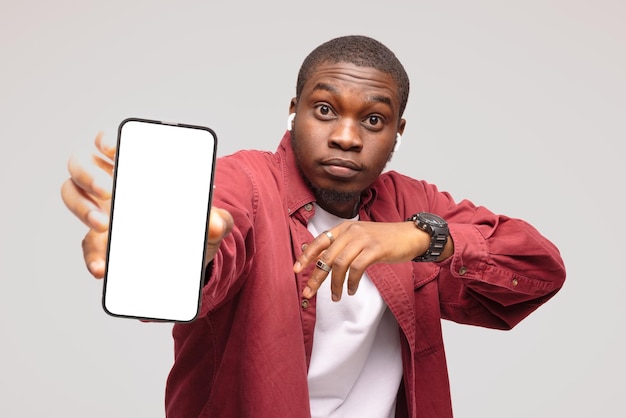 uomo di colore che punta al telefono cellulare con schermo bianco vuoto
