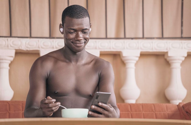 Uomo di colore che usa lo smartphone durante la colazione