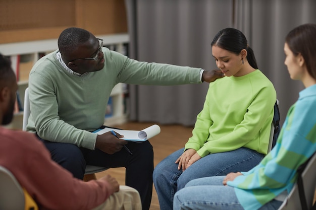 Uomo di colore come psicologo maschio che conforta l'adolescente nella sessione di terapia
