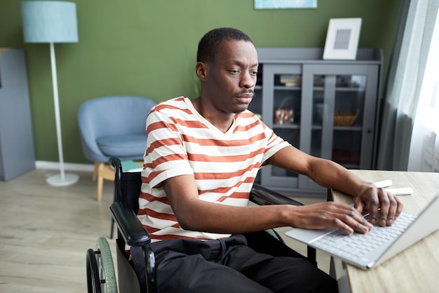 Uomo di colore con disabilità che utilizza il laptop a casa