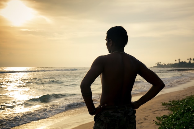 Uomo di colore sulla spiaggia al tramonto