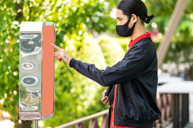 Uomo di consegna asiatico che utilizza il chiosco per ordinare cibo e prelevare questo ordine in linea al cliente al ristorante fast food. Tecnologia online self service nuovo normale concetto di ristorante.