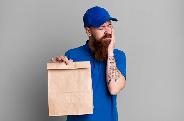Uomo di consegna fresco barbuto capelli rossi adulto giovane con un sacchetto di carta