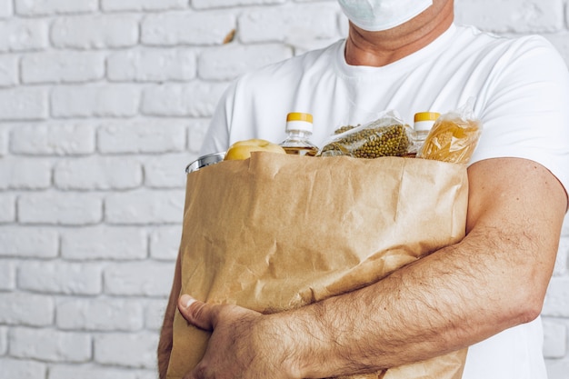 Uomo di consegna in maschera e guanti. Consegna del cibo, concetto di shopping online mentre la pandemia di coronavirus