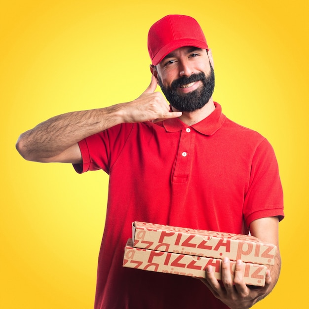 Uomo di consegna pizza facendo gesto del telefono su sfondo colorato
