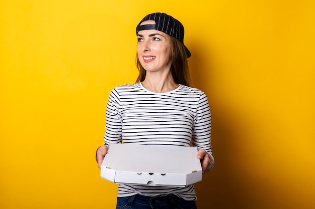 Uomo di consegna pizza giovane donna che guarda al lato mentre si tiene un pacchetto con pizza calda su giallo