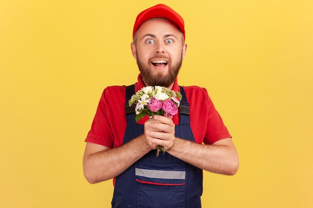 Uomo di consegna stupito con bouquet di fiori che guarda l'obbiettivo con espressione sorpresa