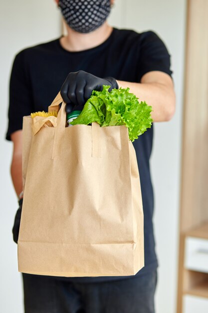 Uomo di corriere in scatola nera di consegna con cibo, consegna senza contatto.