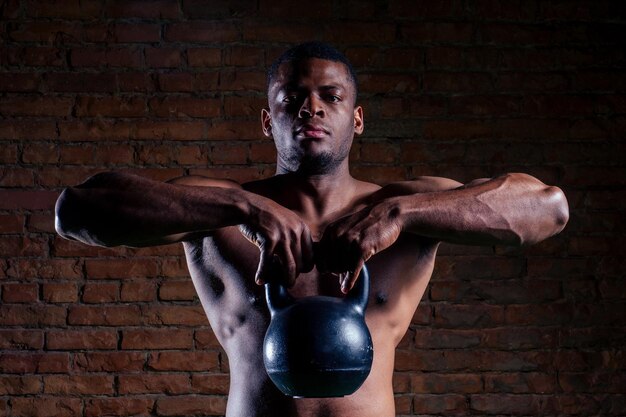 Uomo di forma fisica che fa un allenamento con i pesi sollevando le oscillazioni del kettlebell in palestra