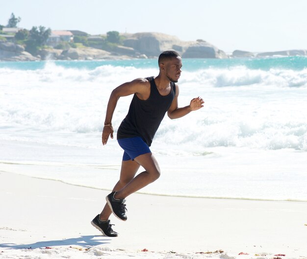 Uomo di forma fisica che funziona sulla spiaggia