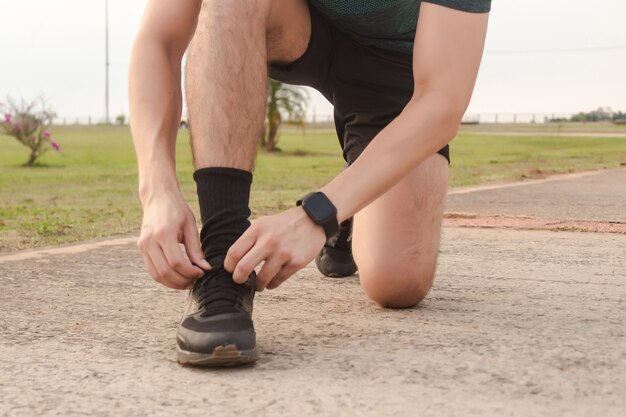 Uomo di forma fisica che si allaccia i lacci delle scarpe nel parco