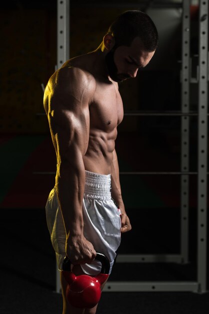 Uomo di forma fisica che utilizza i kettlebell all'interno della palestra