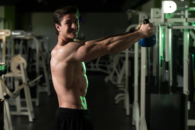 Uomo di forma fisica che utilizza i kettlebell all'interno della palestra