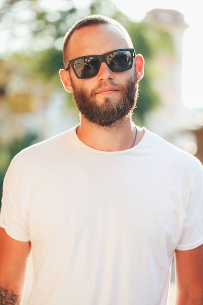 Uomo di hipster che indossa occhiali da sole neri nelle strade urbane della città