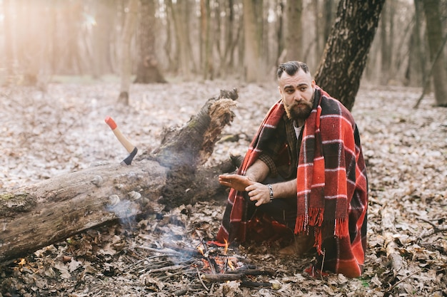 Uomo di hipster che si scalda vicino al fuoco