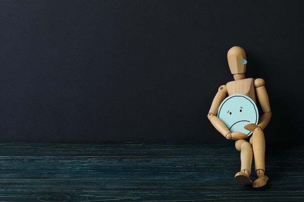 Uomo di legno con triste emoji su sfondo blu scuro spazio per il testo