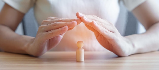 Uomo di legno della copertura della mano Le persone proteggono i concetti di salute e leadership dell'assicurazione sulla vita