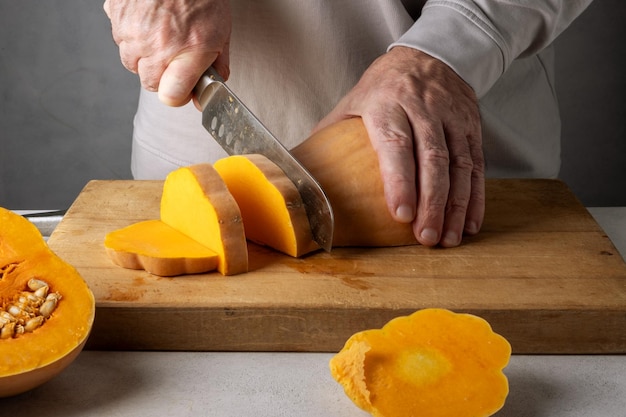Uomo di mezza età caucasico irriconoscibile che taglia la zucca su un tavolo da taglio di legno Focus selettivo