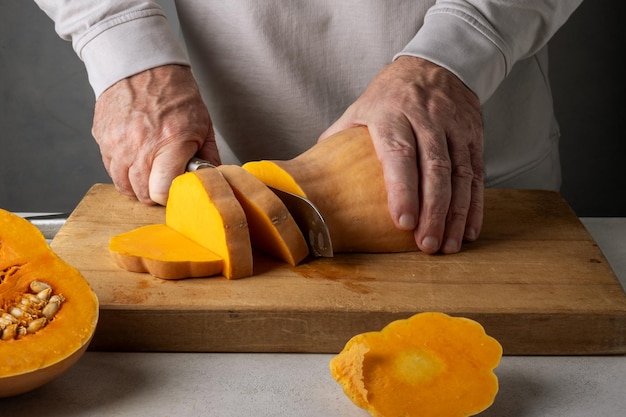 Uomo di mezza età caucasico irriconoscibile che taglia la zucca su un tavolo da taglio di legno Focus selettivo