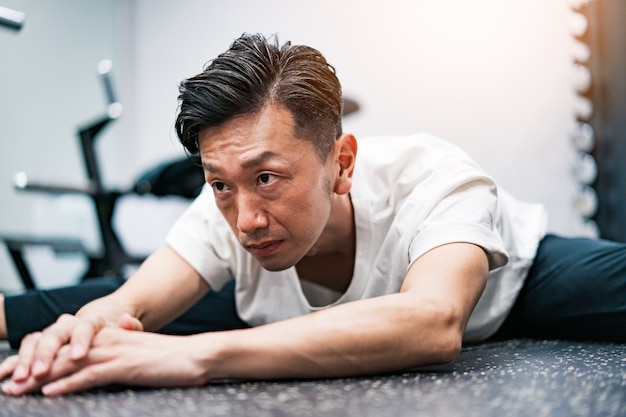 Uomo di mezza età che fa esercizi di stretching in palestra