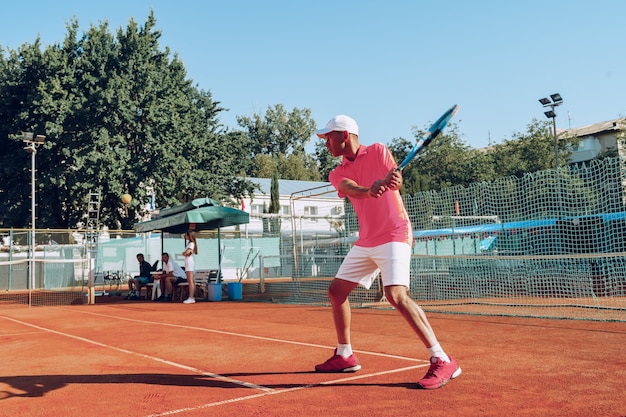 Uomo di mezza età che gioca a tennis sul tennis all'aperto archiviato