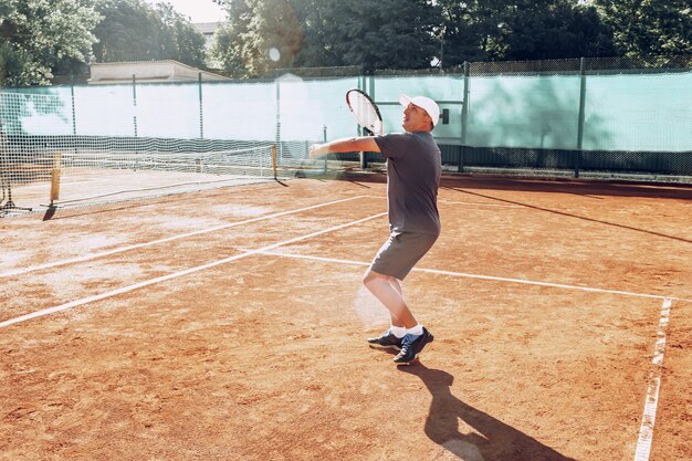 Uomo di mezza età che gioca a tennis sul tennis all'aperto archiviato