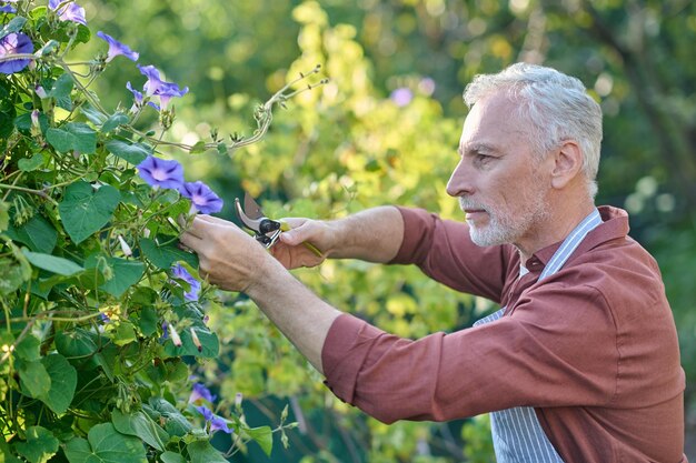 Uomo di mezza età che lavora in un giardino con inventario gtareden