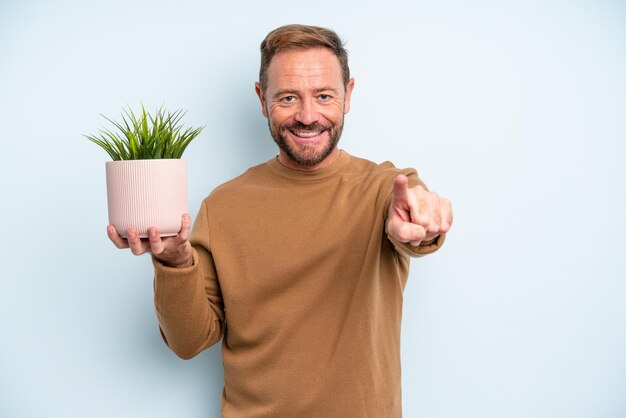 Uomo di mezza età che punta alla telecamera scegliendo te. concetto di vaso per piante