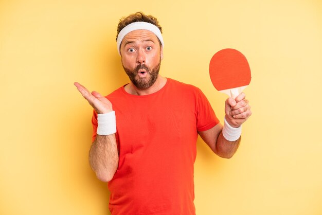 uomo di mezza età che sembra sorpreso e scioccato, con la mascella caduta che tiene un oggetto. concetto di ping pong