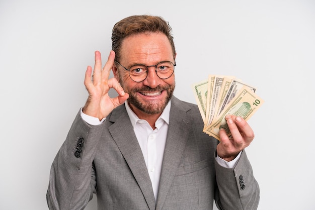 Uomo di mezza età che si sente felice, mostra approvazione con un gesto ok. concetto di banconote in dollari