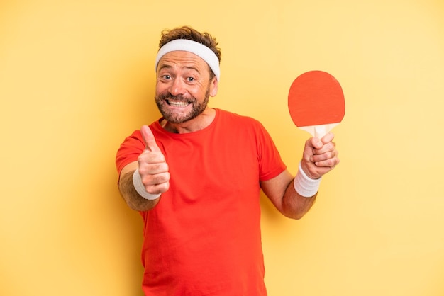 Uomo di mezza età che si sente orgoglioso di sorridere positivamente con il concetto di ping pong pollici in su