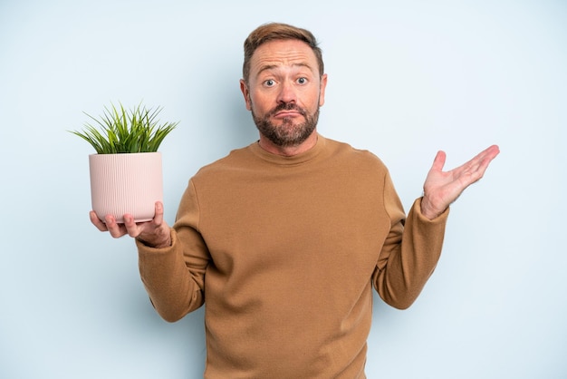 Uomo di mezza età che si sente perplesso, confuso e dubbioso. concetto di vaso per piante