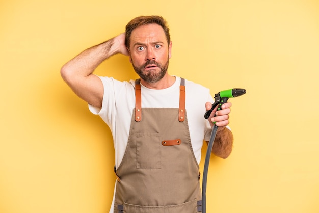 Uomo di mezza età che si sente stressato, ansioso o spaventato, con le mani sulla testa. concetto di tubo da giardiniere