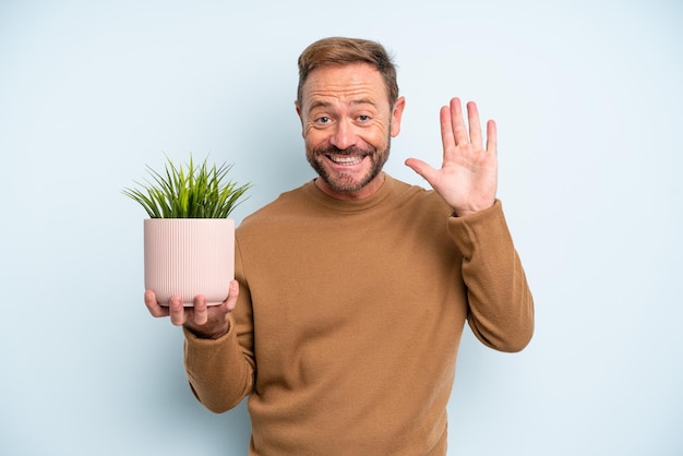 Uomo di mezza età che sorride felicemente, agitando la mano, accogliendoti e salutandoti. concetto di vaso per piante