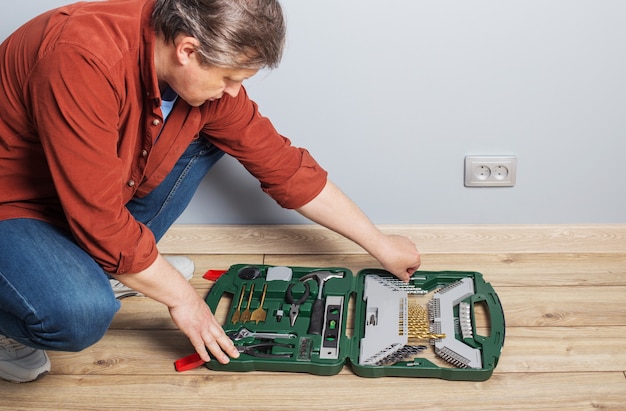 Uomo di mezza età con set di strumenti di riparazione sul pavimento di legno