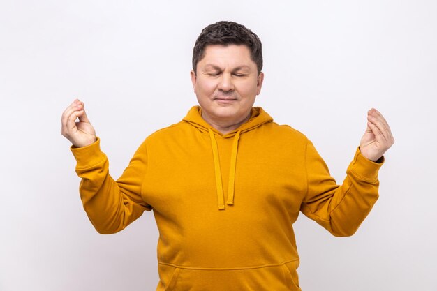 Uomo di mezza età in piedi con le braccia alzate e facendo yoga meditando esercizio gesto mudra