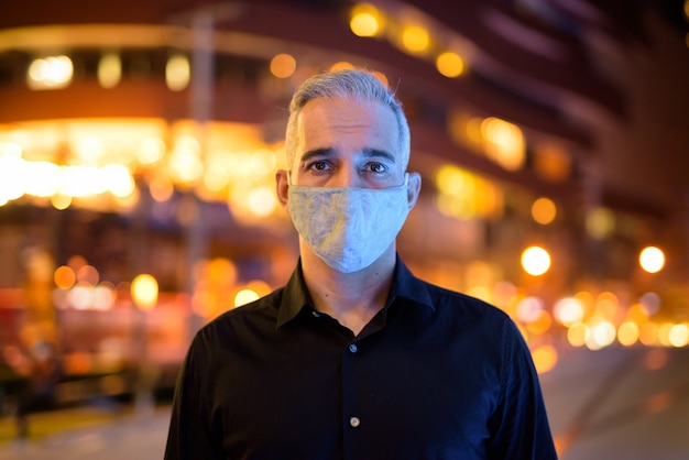 Uomo di notte per le strade che indossa una maschera facciale protettiva per proteggersi dal virus corona covid 19