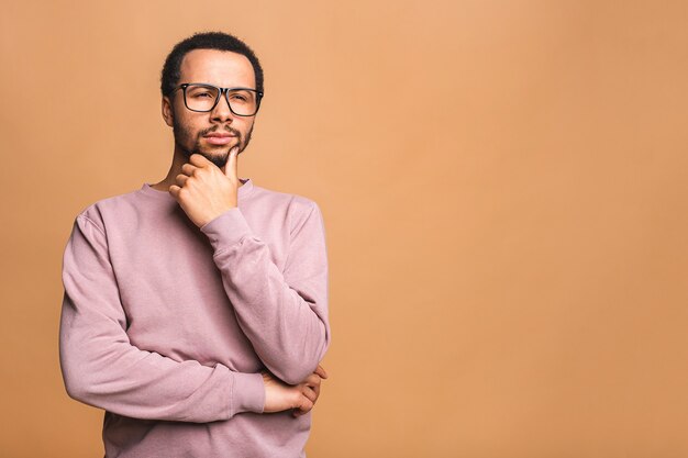 Uomo di pensiero con espressione seria alla ricerca, posa isolata contro il beige.