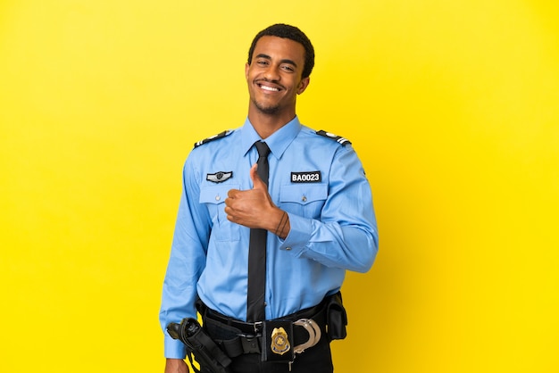 Uomo di polizia afroamericano su sfondo giallo isolato che dà un gesto di pollice in alto