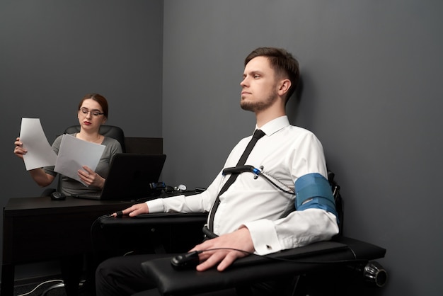 Uomo di prova della donna con il poligrafo nella stanza grigia.