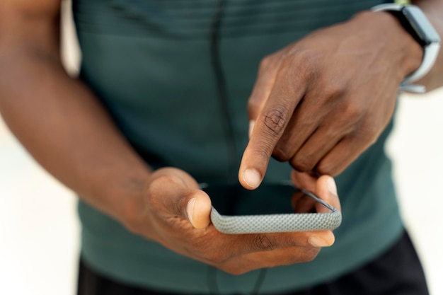 Uomo di razza mista che gira musica sul suo smartphone mentre è in piedi per strada