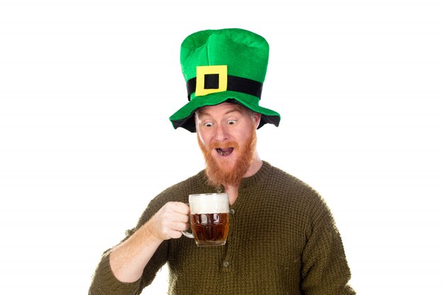 Uomo di redhead con un grande cappello verde che beve una birra