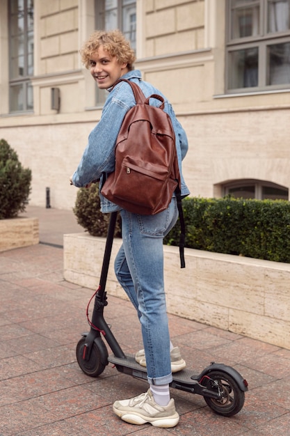 Uomo di smiley che guida scooter elettrico in città