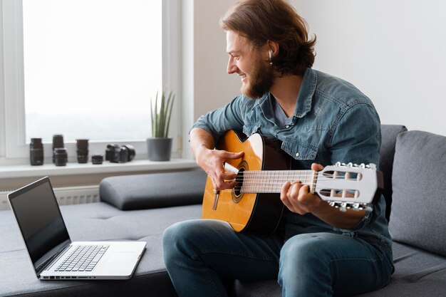 Uomo di smiley del colpo medio che gioca chitarra