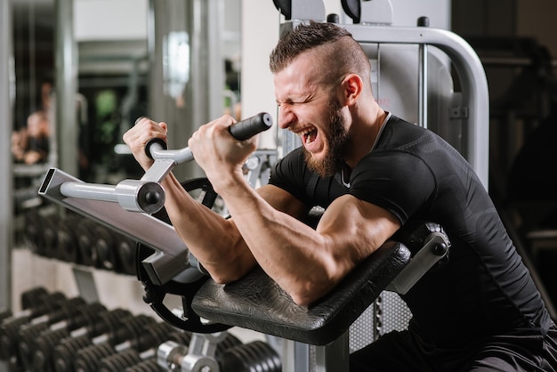 Uomo di sollevamento pesi in palestra lavorando sodo